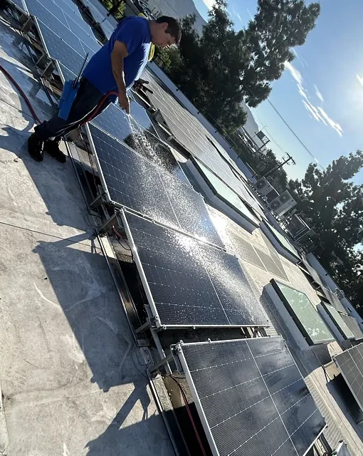 Technician cleaning rooftop solar panels at a commercial property in Burbank.